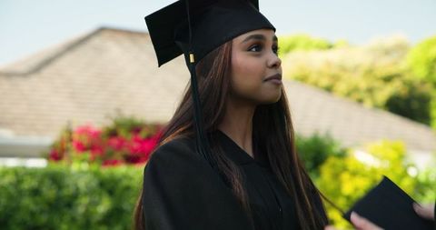 Young Woman in Graduation Gown Outdoors on Sunny Day
