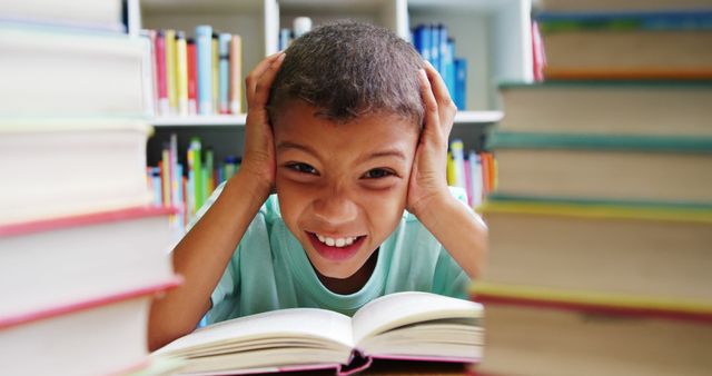 Young boy smiling while reading book in library, bookshelves in background. Great for illustrating children's educational materials, literacy promotions, school website content, and library advertisements.