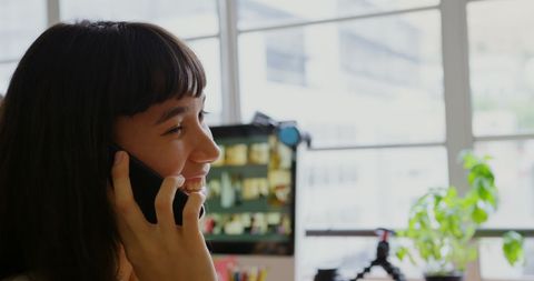Caucasian graphic designer talking on mobile phone in modern office