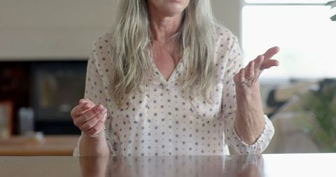Senior woman gesturing while talking at home