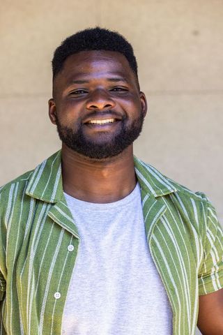 Confident african man smiling in green striped shirt, casual headshot on neutral backdrop