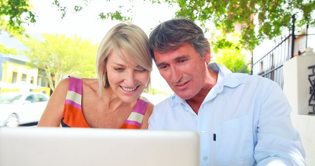 Smiling Middle-aged Couple Using Laptop Outdoors - Download Free Stock Images Pikwizard.com