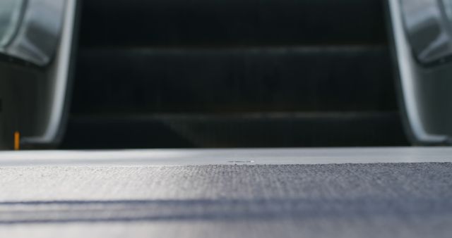 Blurred close-up of escalator steps with focus on top level. Ideal for use in transportation, urban living, and industrial themes. This can also highlight the machinery aspect in commercial designs or be used in promotional material referring to public transportation.