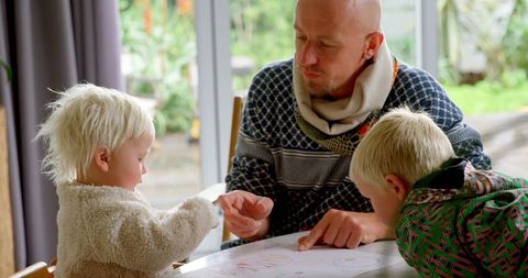 Father engaging with children in creative art activity at home