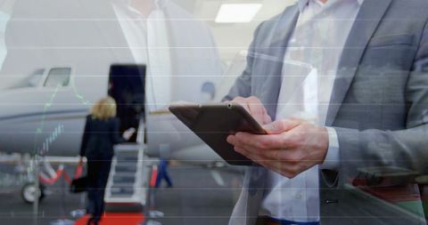 Executive holding tablet checking flight charts beside private jet on airport ramp during boarding