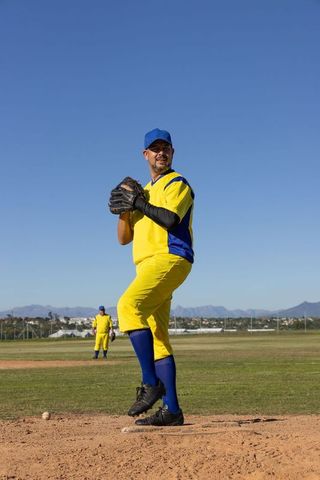 Right-handed pitcher preparing windup on baseball mound in yellow and blue uniform