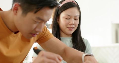 Asian couple cooking together in bright modern kitchen preparing healthy meal