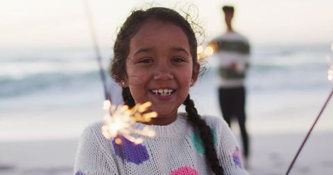 Joyful Girl Enjoying Sparklers by Beach at Sunset