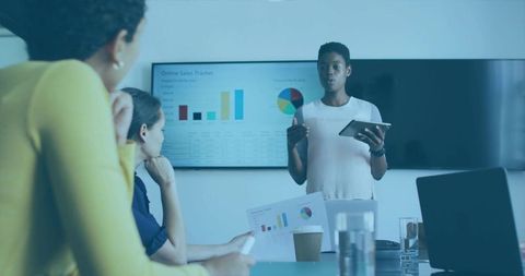 Businesswoman presenting sales tracker on tablet during meeting with charts and dashboard