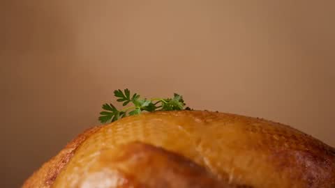 Garnishing roasted chicken breast with fresh parsley sprig at tabletop macro close-up