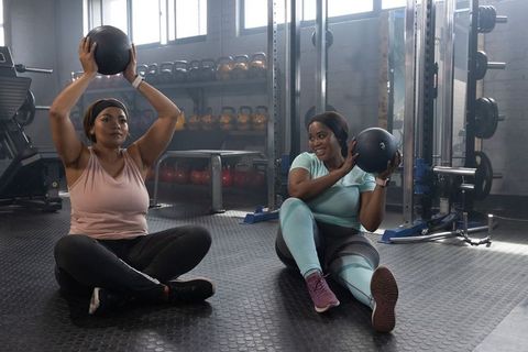 African american women exercising with medicine balls in gym during strength training session