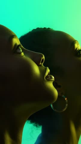 Vertical video featuring two models gazing upward in shifting neon lighting with hoop earrings