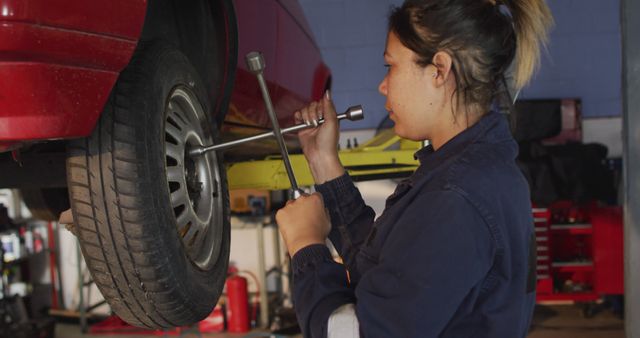 Female mechanic changing tires of the car using a wheel wrench at a car service station. automobile repair service