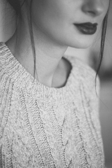 Elegant close-up captures details of a woman's knitted sweater in monochrome. Emphasizes her lips and soft facial features. Ideal for fashion magazines, clothing advertisements, winter season promotions, style blogs, and cozy winter-themed presentations.