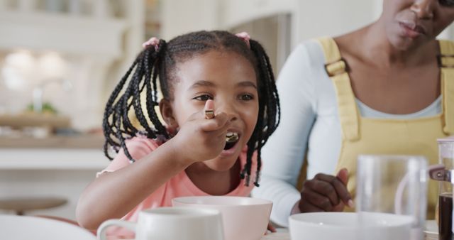 Happy African American Girl Eating Breakfast with Mother - Download Free Stock Images Pikwizard.com