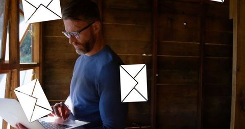 Man Concentrating on Laptop in Rustic Cabin Maintaining Email Efficiency