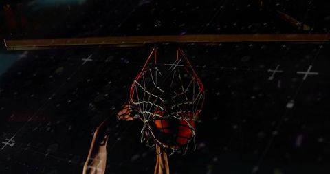 Power dunk driving through rim and net under arena spotlight