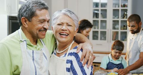 Smiling Senior Couple with Family Cooking Together in Kitchen