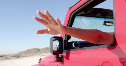 Arm Outstretched from Red Vehicle Signaling Freedom on Road Trip