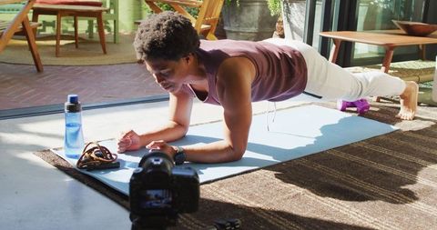 Fit man filming home workout vlog with plank exercise
