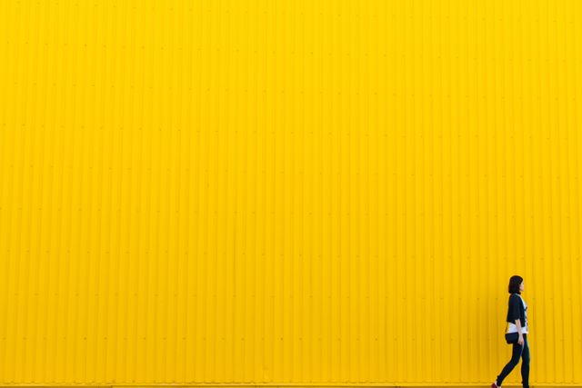 Woman Walking by Vibrant Yellow Wall - Download Free Stock Photos Pikwizard.com