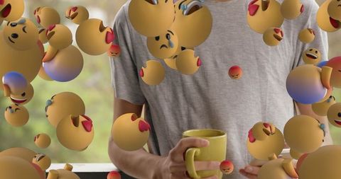 Person with yellow mug surrounded by floating emojis expressing emotions