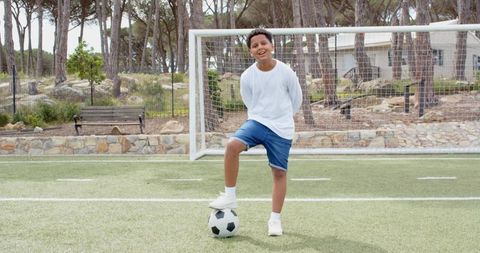 Confident Young Athlete Posing with Soccer Ball on Field