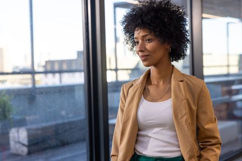 Confident Businesswoman Standing by Window in Modern Office