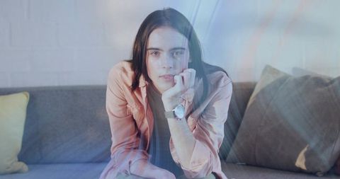 Thoughtful Woman Leaning on Hand Meeting Gaze on Sofa with Soft Light Lens Flare