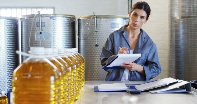 A middle-aged Caucasian woman, a quality control inspector, is evaluating products in an industrial setting, with copy space. Her focused expression and clipboard suggest she's ensuring standards are met in the production facility.