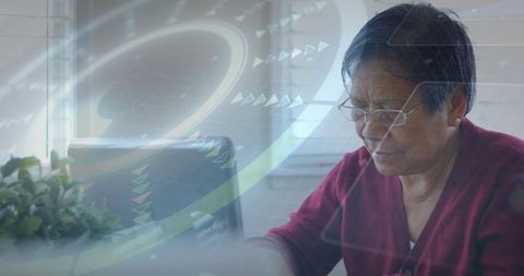 Chinese senior woman using laptop at home with futuristic hud overlay for remote work