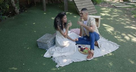 Diverse Couple Toasting with Drinks at Peaceful Garden Picnic