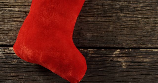A red Christmas stocking hangs against a rustic wooden background, with copy space. Stockings like this are traditionally filled with small gifts and treats during the holiday season.