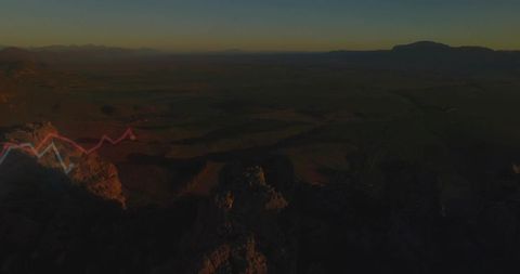Sunlit jagged cliffs over wide valley at golden hour with red blue data zigzag overlay