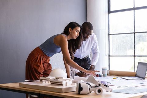 Architects Collaborating on Project Using Laptop and Blueprints