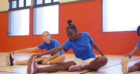 Diverse Young Girls Stretching in School Gym Class Setting