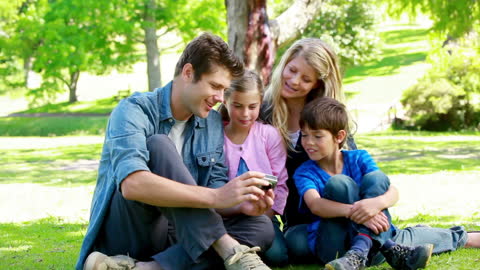Family Enjoying Photos on Digital Camera in Sunny Park