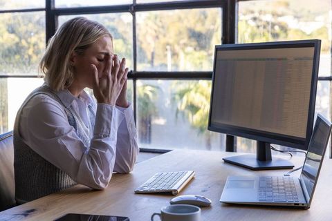 Frustrated Businesswoman in Modern Workspace with Electronic Devices