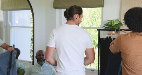Groom prepares for wedding with friends in bright room