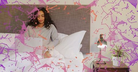 Woman working remotely from bed with cat, relaxing with laptop and lamp