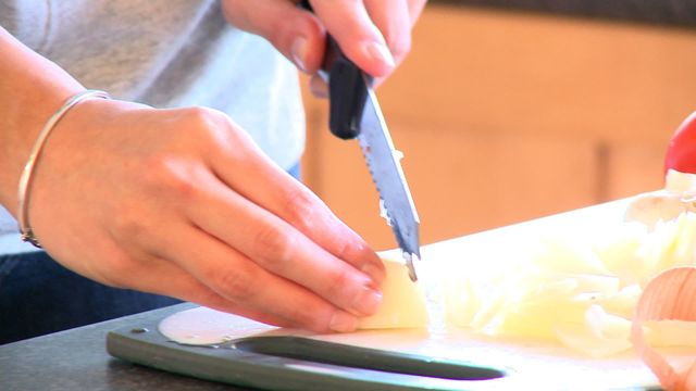 Zoom on woman cutting onions at home