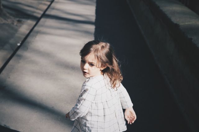 Little Girl Walking Alone on Sunlit Urban Sidewalk - Download Free Stock Photos Pikwizard.com