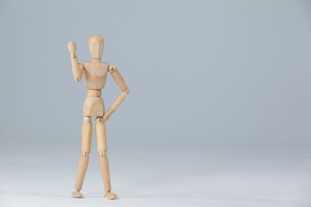 Wooden figurine standing and showing his fist against white background