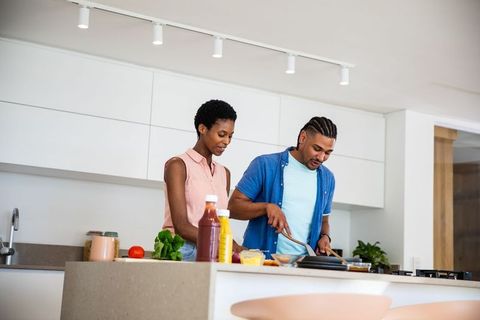 Diverse Couple Joyfully Cooking at Home in Modern Kitchen