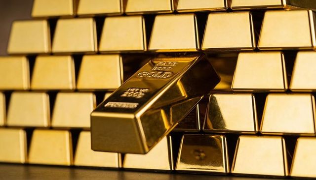 Protruding polished gold bullion bar showing purity stamp among stacked bars luxury wealth