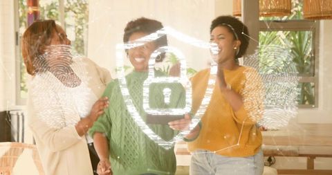 Three women sharing tablet laughing with digital security shield overlay in cozy home