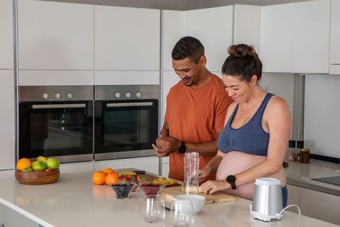 Diverse Couple Preparing Fresh Smoothie in Contemporary Kitchen
