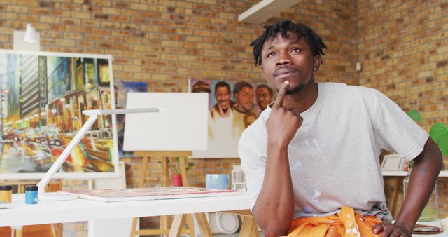 Portrait of pensive african american male painter in artist studio. art, creative and leisure time concept.
