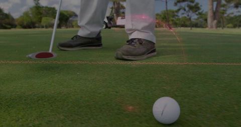 Golfer lining up putt on green with ball near hole and red-rim cup, low-angle close-up
