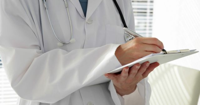 Doctor Writing on Clipboard Holding Stethoscope in Office - Download Free Stock Images Pikwizard.com